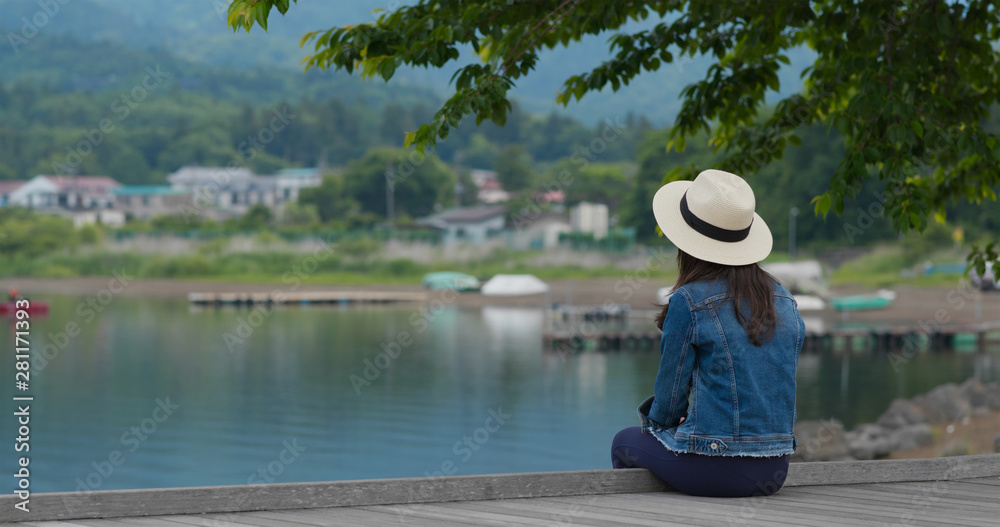 Woman sit at the lake side and look around
