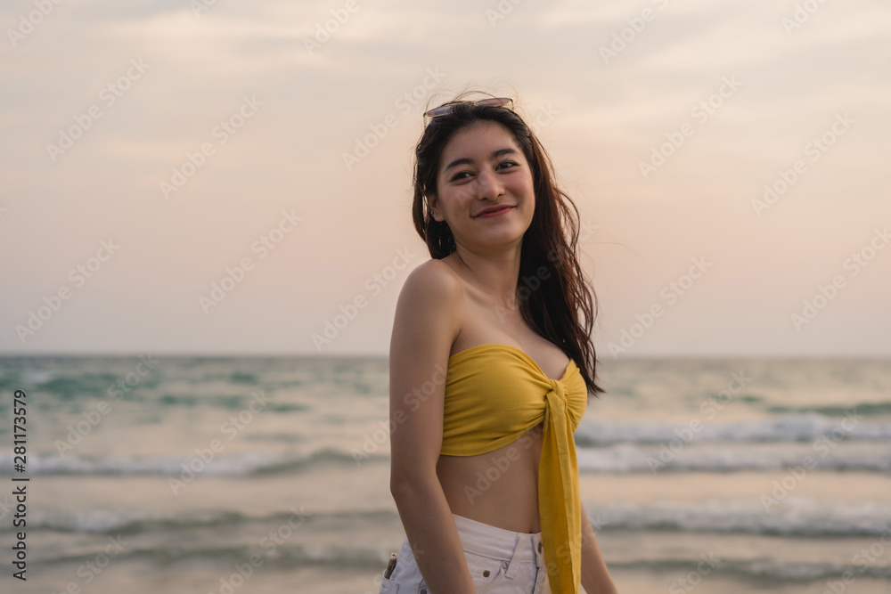Young Asian woman feeling happy on beach, beautiful female happy relax smiling fun on beach near sea when sunset in evening. Lifestyle girl travel holiday vacation summer concept.