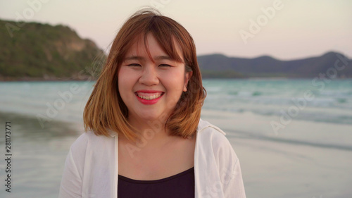 Young Asian woman feeling happy on beach, beautiful female happy relax smiling fun on beach near sea when sunset in evening. Lifestyle women travel on beach concept. © tirachard