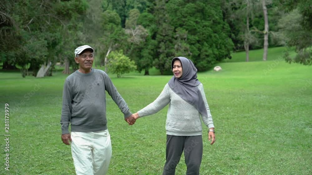 portrait of asian muslim senior couple walking in the garden together portrait of asian muslim senior couple walking in the garden together