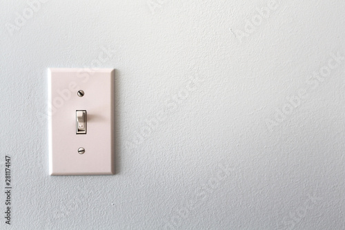 A white light switch on a grey wall photo