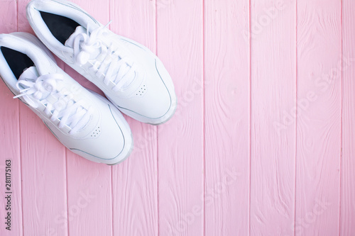White sneakers on light pink background.Toned image. Women's shoes. stylish white sneakers