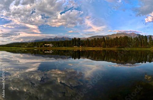 Panoramic view Columbia Lake. Beautiful reflections of mountains  trees and a vacation cottage in calm lake in the morning. Columbia lake. British Columbia. Canada