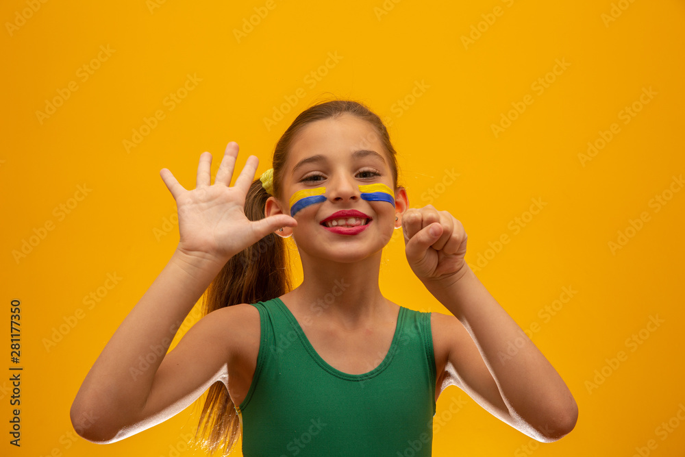 Football supporter, Brazil team. World Cup. Beautiful little girl cheering for her team on yellow background Football supporter, Brazil team. World Cup. Beautiful little girl cheering for her team on yellow background