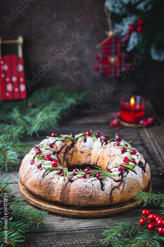 Traditional homemade christmas cake holiday dessert with cranberry and chocolate with new year tree decoration on vintage wooden table background. Rustic style.