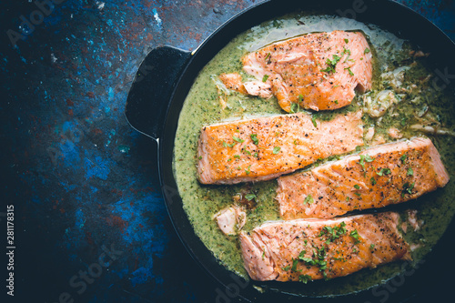 Grilled Salmon with spinach and garlic cream sauce in a frying pan, top view