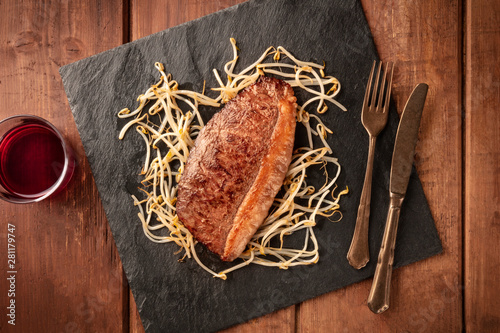 Kobe meat, wagyu beef steak, cooked, shot from above with soy sprouts and red wine photo