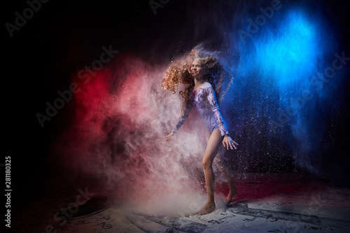 Beautiful teen girl with long blonde curly hair in a dark room with colored lights and clouds of flour © keleny