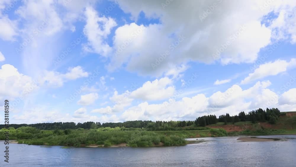Clouds run across the blue sky. Time lapse. Below the river flows and the forest grows Clouds run across the blue sky. Time lapse. Below the river flows and the forest grows