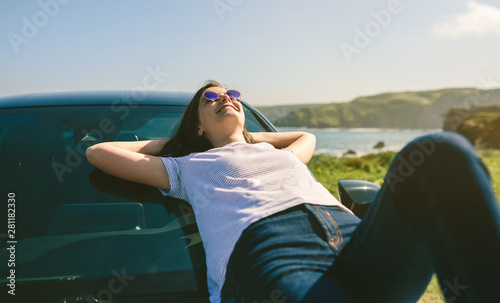 Happy young girl resting lying on the windshield of the car