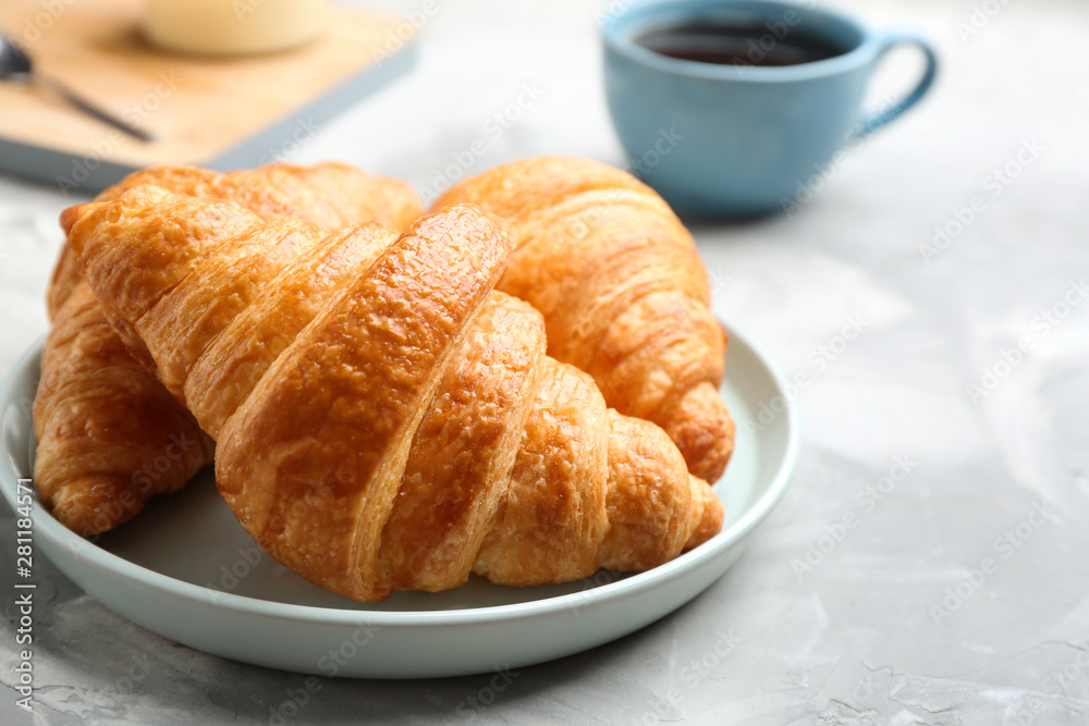 Plate of fresh croissants on grey table, closeup. French pastry