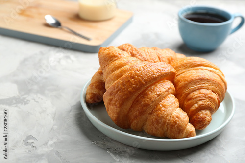 Plate of fresh croissants on grey table, space for text. French pastry