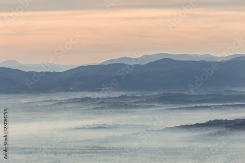 Fog filling a valley in Umbria (Italy) at dawn, with layers of mountains and hills and various shades of blue