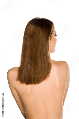 Back view of young nude woman with long hair on white background
