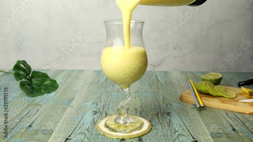 Pouring Pina Colada from blender into glass on table