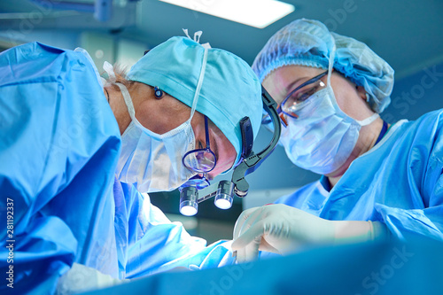 Fotografie, Obraz A surgeon's team in uniform performs an operation on a patient at a cardiac surgery clinic