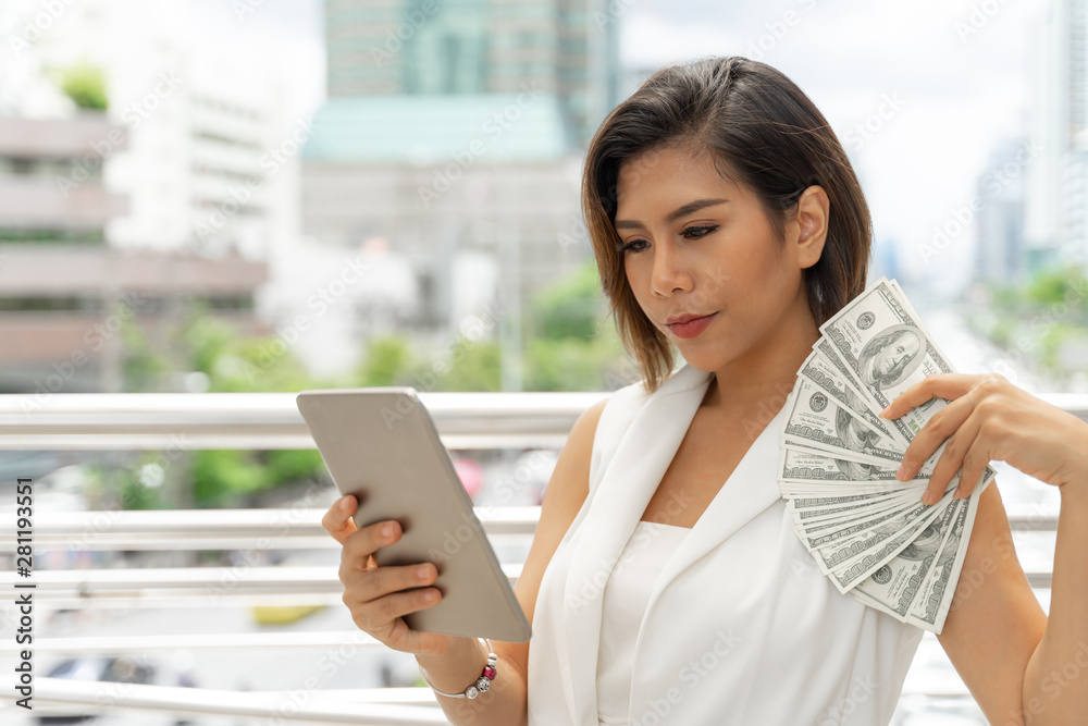 Successful beautiful  asian business  young woman using smart phone and money US dollar bills in hand , business concept