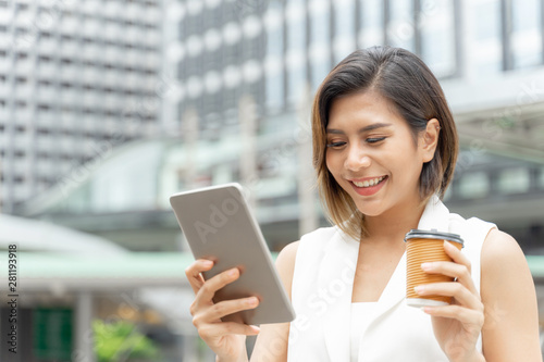 Successful beautiful asian business young woman using smart phone and coffee cup in hand , business concept