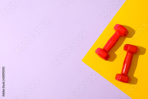 Dumbbells for fitness on two tone background, space for text