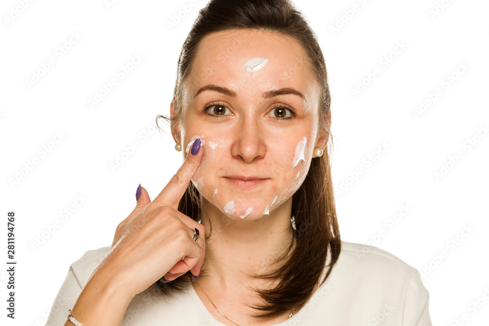 young smiling women applied the cream on her face on white background young smiling women applied the cream on her face on white background
