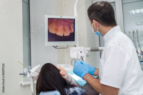 Dentist checking patient s teeth with camera  looking on screen