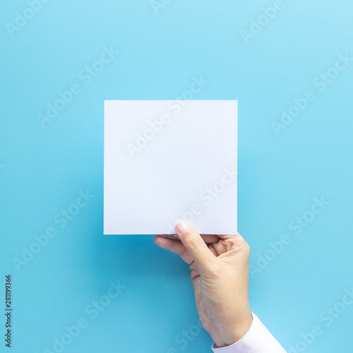 woman hand holding blank paper sheet isolated on blue background with copy space.