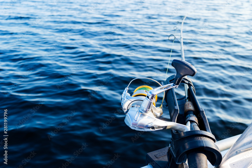 Fishing rod spinning with the line close-up. Fishing rod in rod holder in fishing  boat due the fishery day at the sunset. Fishing rod rings. Fishing tackle.  Fishing spinning reel. Photos
