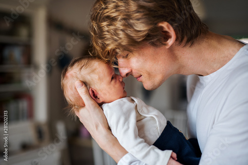 A young father with a newborn baby son at home.