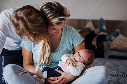 Young parents with newborn baby and small toddler son at home. photo