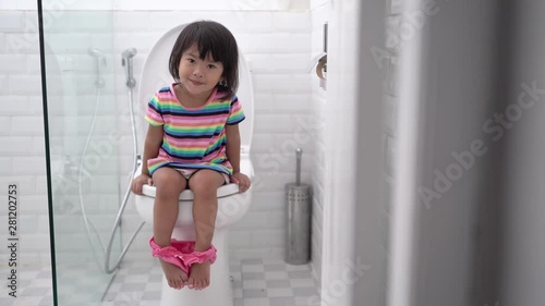 pooping in the toilet. cute asian kid push it hard while sitting on toilet
