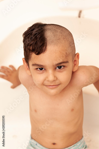 Six-year boy at haircutting at home. Father cut half of the son s hair off at the bathroom
