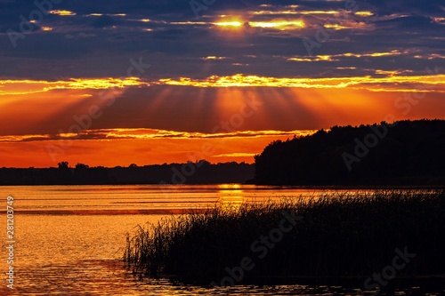 Romantyczny zachód słońca nad jeziorem z promieniami słońca w chmurach