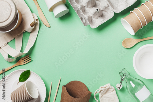 Organic cotton bag, glass jar and recycled tableware on green background top view. Zero waste, eco friendly, plastic free concept. Flat lay. photo