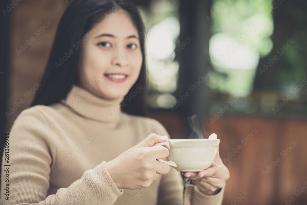 Young woman holding a cup of hot coffee in nature view Young woman holding a cup of hot coffee in nature view