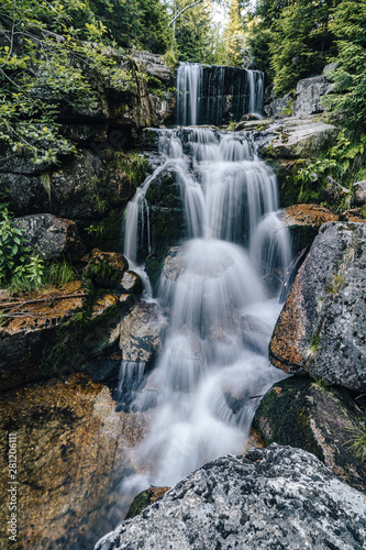 Waterfall photograph. Long exposure photo of a beautiful waterfall of Jedlova  Jizerske mountains  Czechia. Motion blurr water in a mountain creek in a deep forest. Alaska like stream with a rocks.