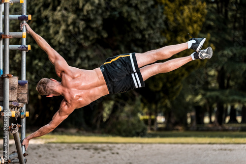 Fit Muscular man performing calisthenics fitness  workout on outdoor scaffolding photo