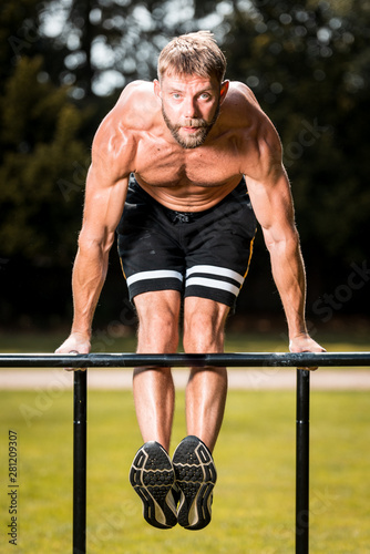 calisthenics hand stand fitness, sport, training and lifestyle concept - young man exercising on parallel bars outdoors