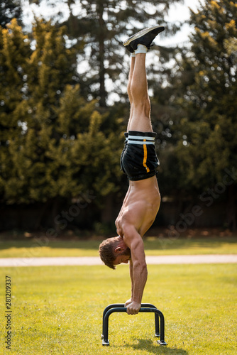 calisthenics hand stand fitness, sport, training and lifestyle concept - young man exercising on parallel bars outdoors