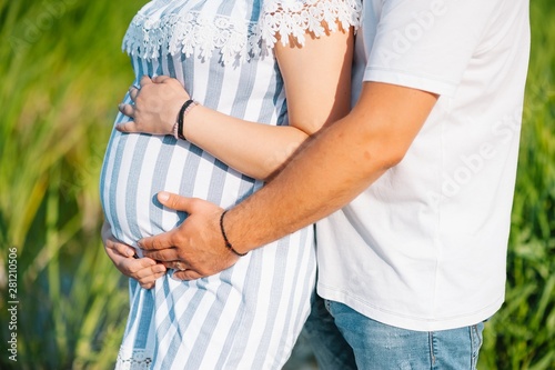 Image of pregnant couple. Husband touching his wife belly with hands. Pregnant woman outdoors