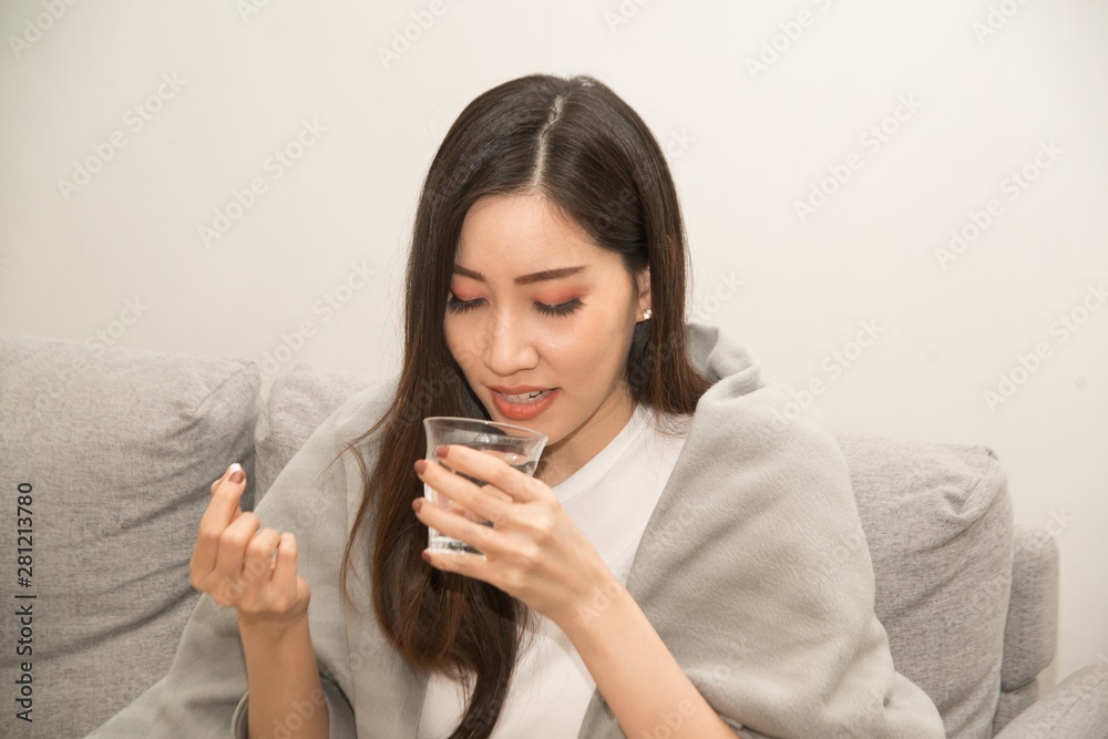 Asian young woman wrapped in a blanket and during illness and taking antipyretics.. Asian young woman wrapped in a blanket and during illness and taking antipyretics..