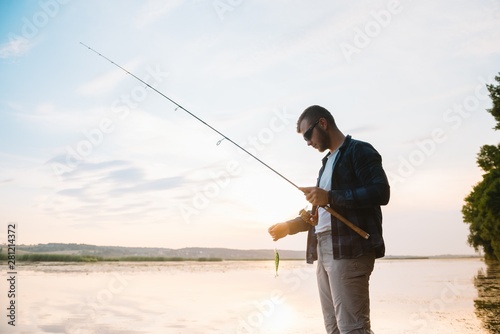 Young man fishing at misty sunrise