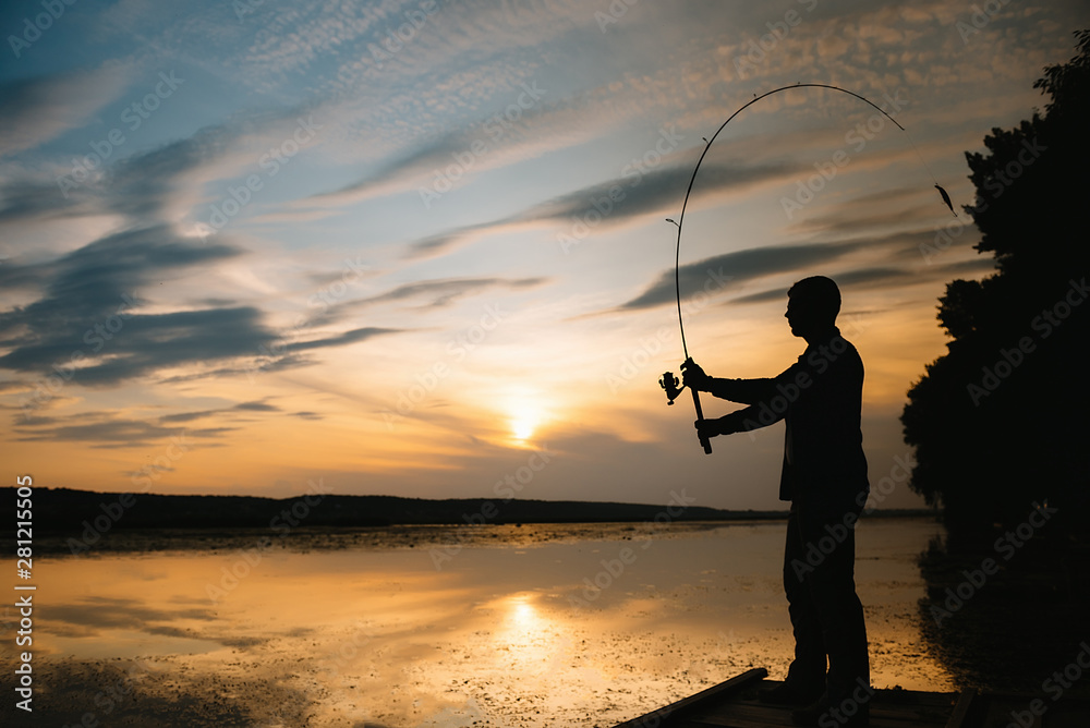 A fisherman silhouette fishing at sunset. Freshwater fishing, catch of fish