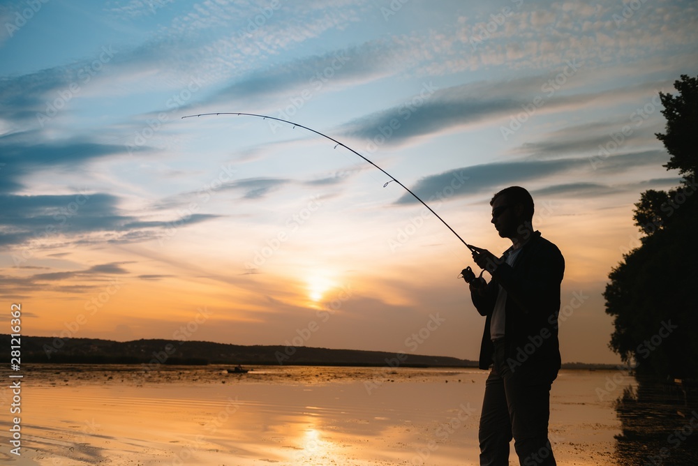 Fishing. spinning at sunset. Silhouette of a fisherman