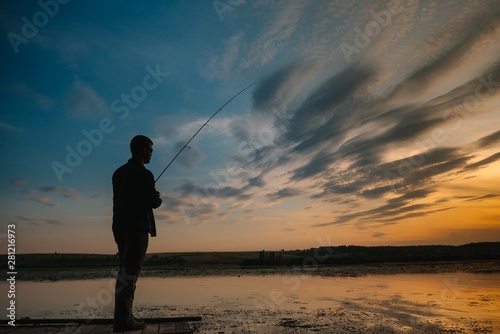 Fishing. spinning at sunset. Silhouette of a fisherman