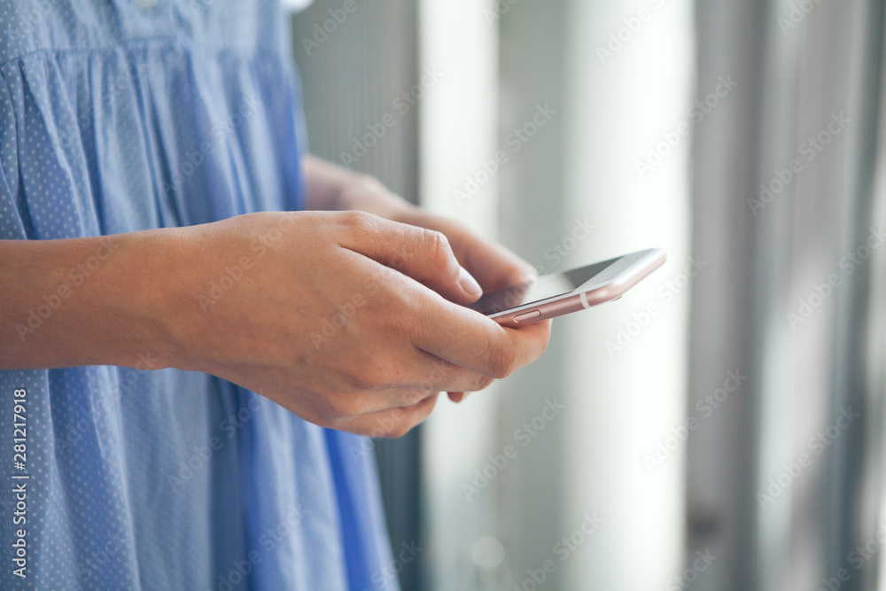 Close up of woman in blue dress holding phone and using internet. Selective focus