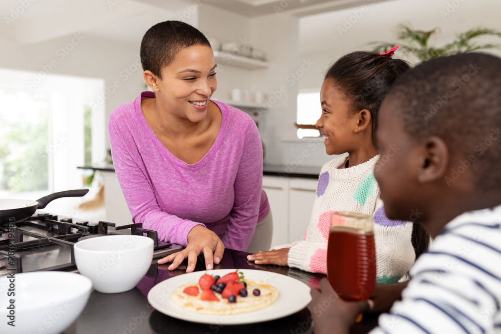 Mother and children preparing food on a worktop in kitchen