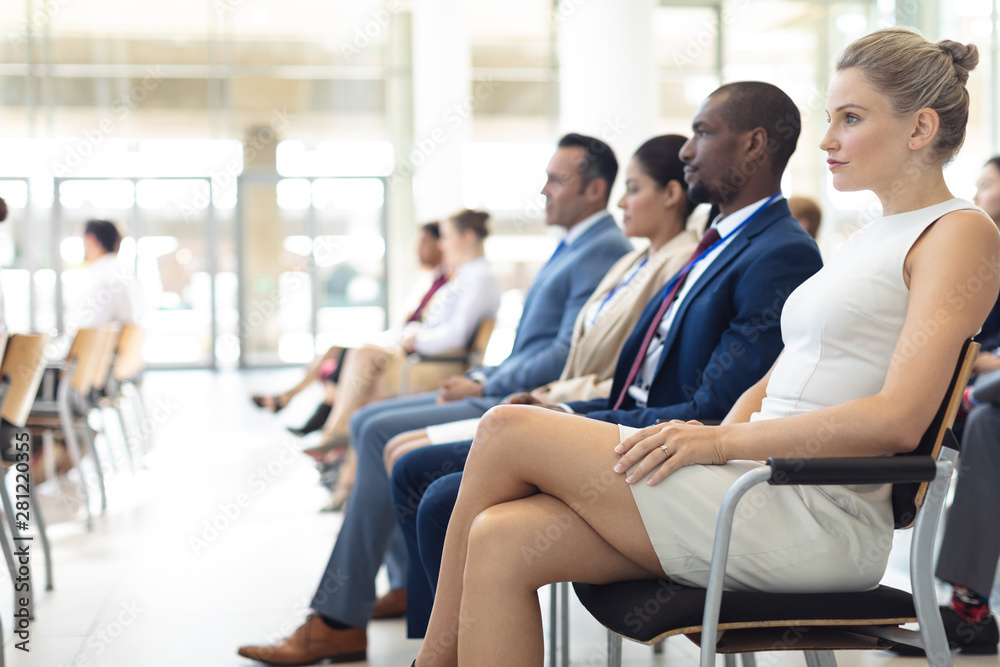 Group of diverse executives sat in conference room, looking straight ahead