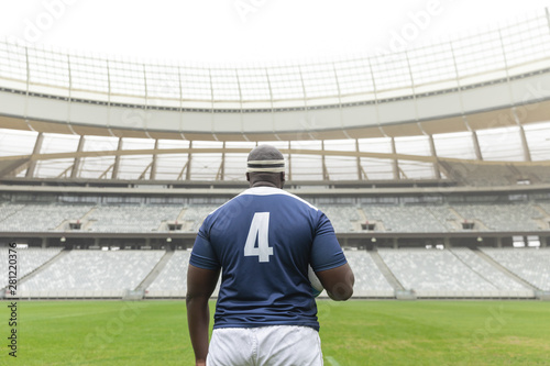 African American rugby player standing with rugby ball in the stadium