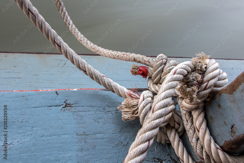 Fototapeta premium Boat rope tied to a wooden post on a floating boat railing, close up.