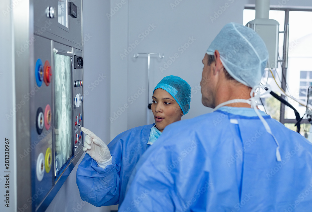 Surgeons discussing over x-ray report on x-ray light box in operating room Surgeons discussing over x-ray report on x-ray light box in operating room